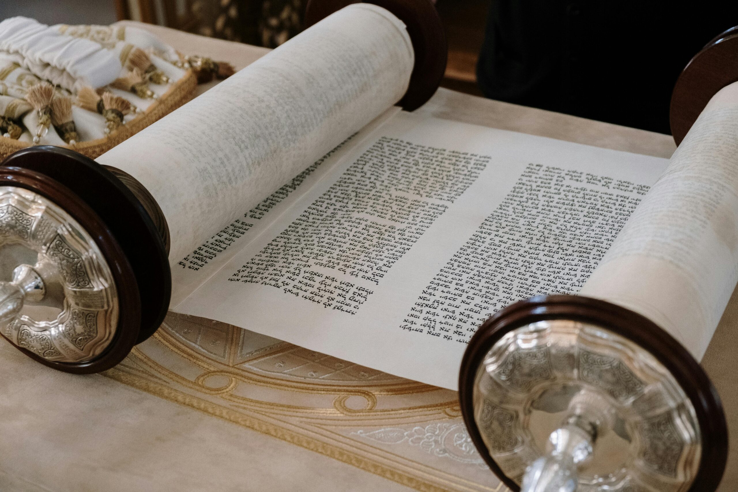 A close-up view of an open Sefer Torah on a synagogue table, highlighting intricate details.